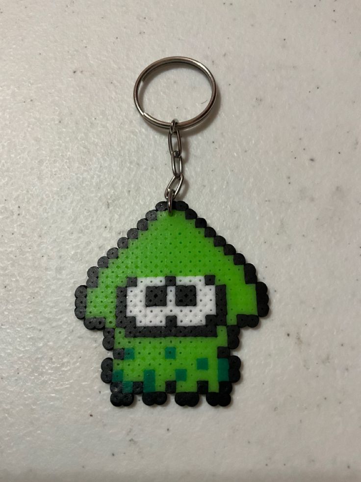 a green pixel keychain with an evil face on it