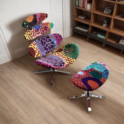 two colorful chairs sitting on top of a hard wood floor next to a book shelf