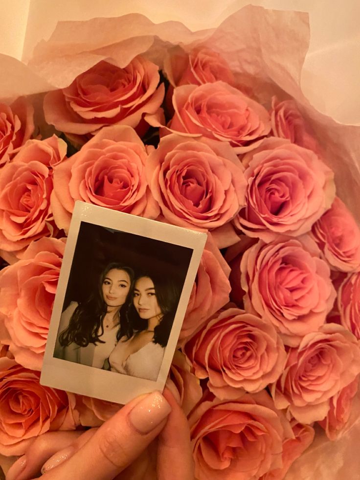 a person holding a bouquet of pink roses with a polaroid photo in the middle