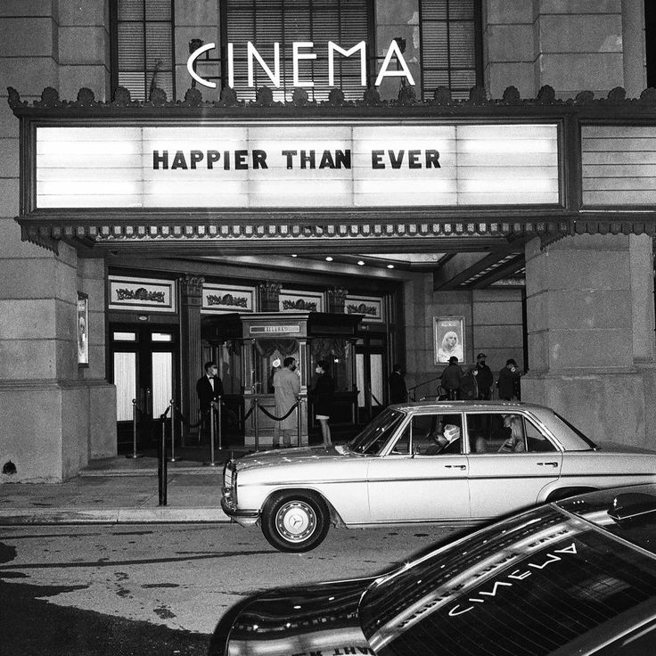 cars parked in front of a movie theater with the marquee saying'happy than ever '