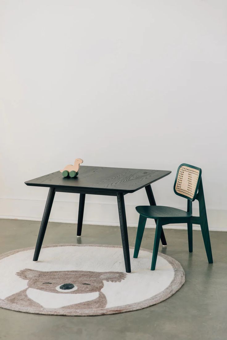 a small table and two chairs in a room with white walls, carpet and rugs on the floor