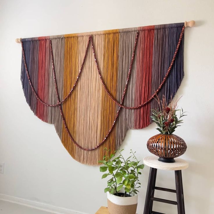 the wall hanging is decorated with multicolored yarns and bead trimming