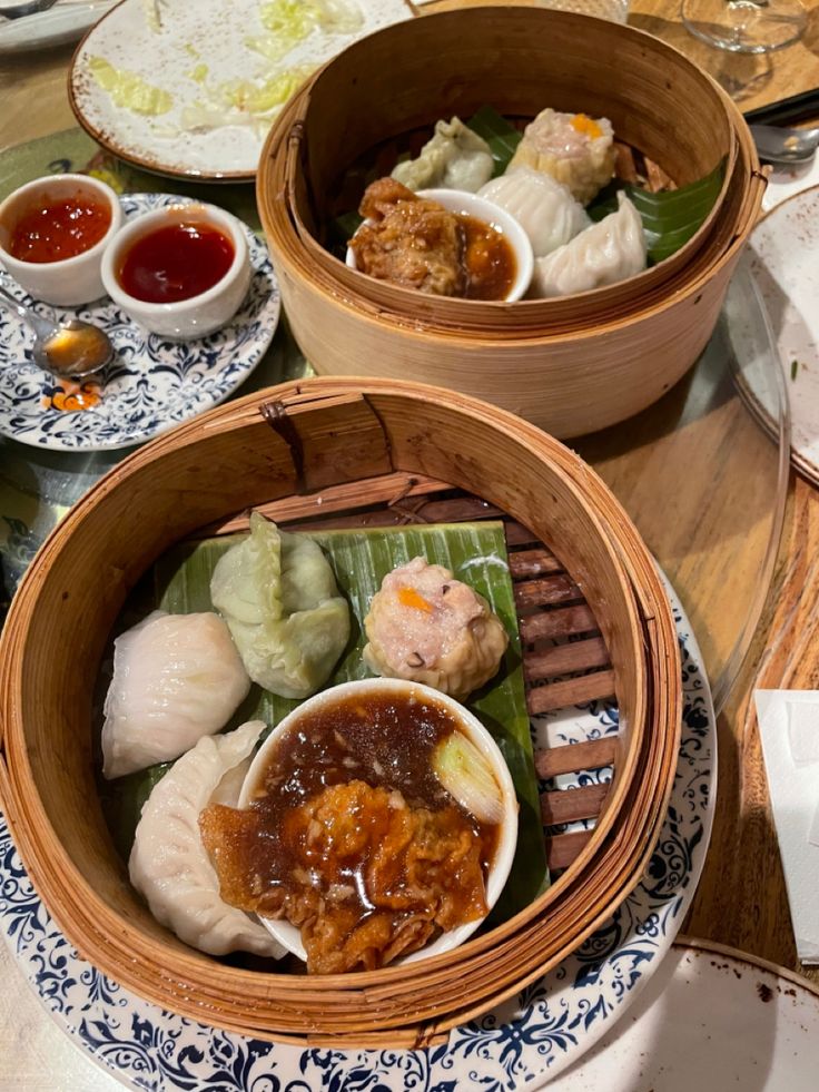 two wooden bowls filled with different types of food on top of a table next to plates