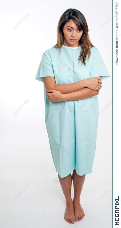 a woman in a hospital gown standing with her arms crossed