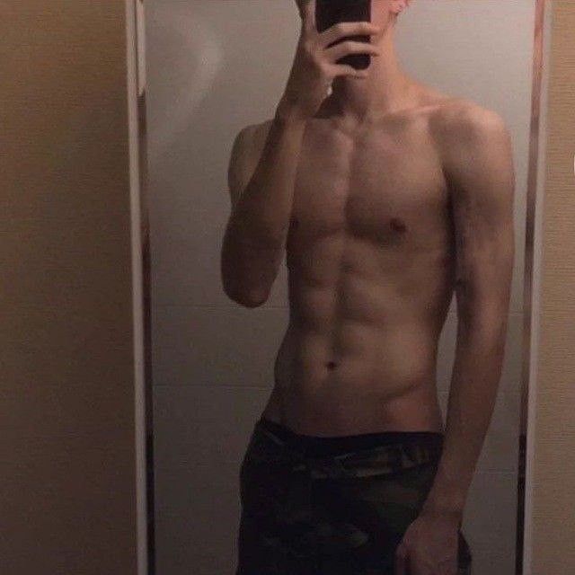 a shirtless man taking a selfie in front of a mirror with his cell phone