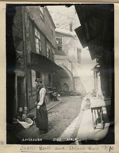 an old black and white photo of people standing in the street