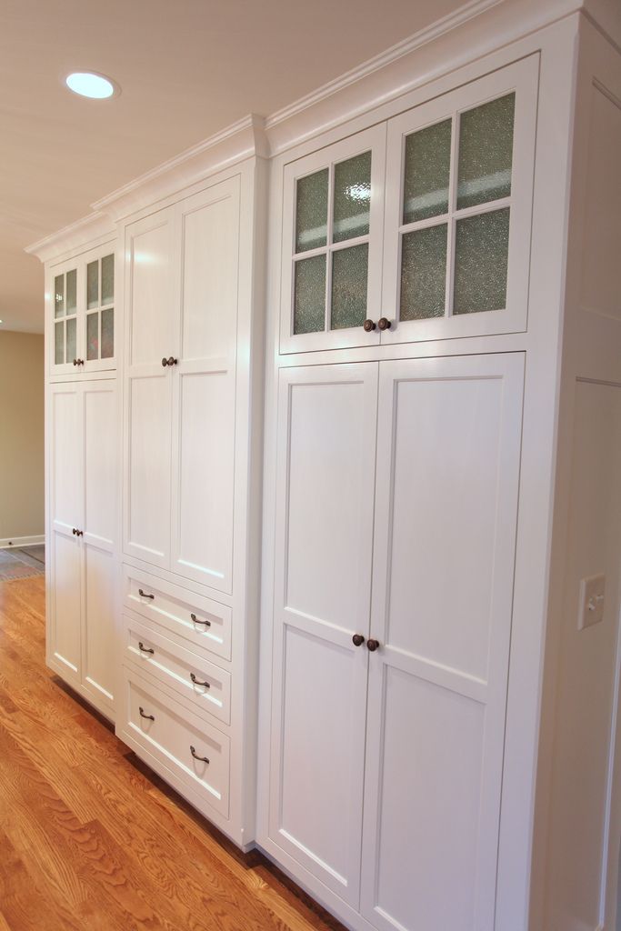 an empty kitchen with white cabinets and wood floors