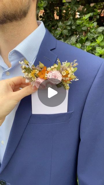 a man in a blue suit is holding a boutonniere with flowers on it