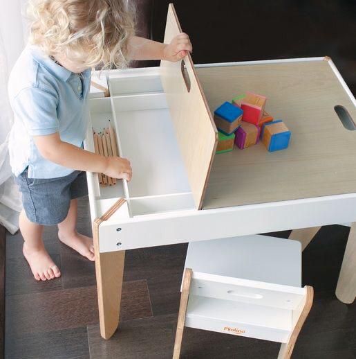 a young child playing with wooden toys in a play table that is made out of white plywood