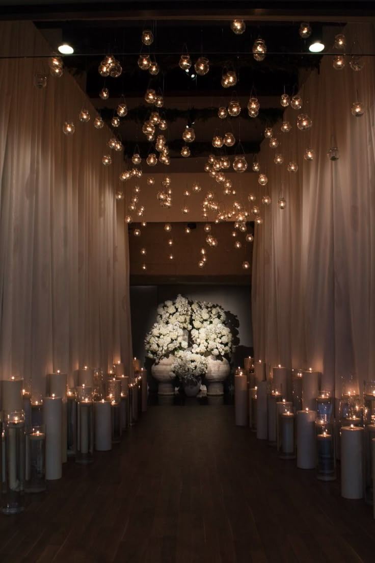 a room filled with lots of white candles and lights hanging from it's ceiling