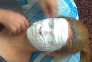 a woman with a facial mask on laying down