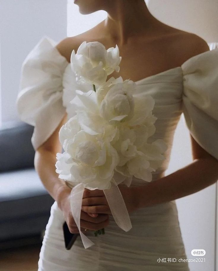 a woman in a white dress holding a bouquet of flowers