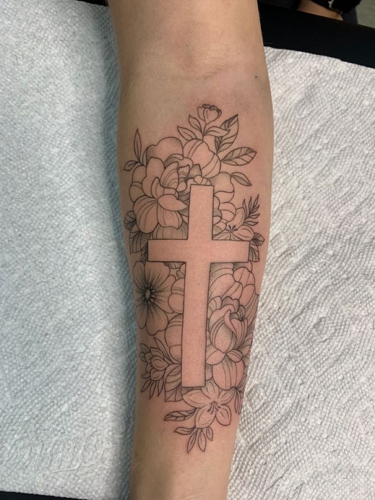 a cross with flowers around it on the leg