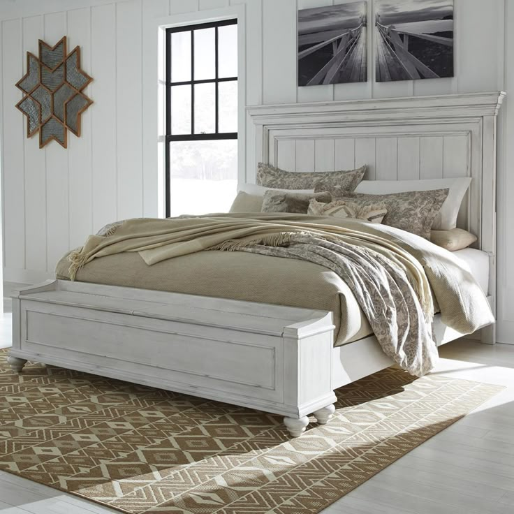 a white bed sitting in a bedroom on top of a carpeted floor next to a window