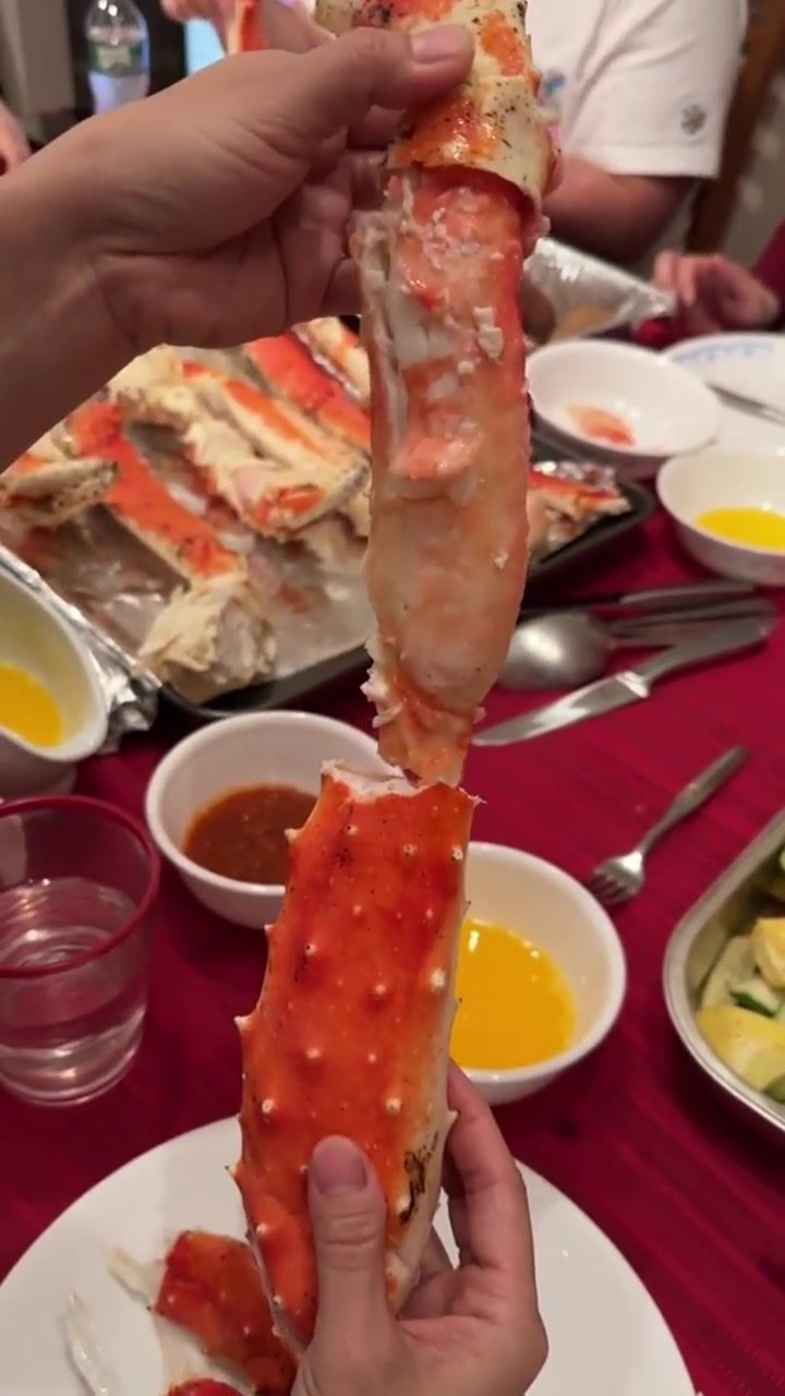 a person is holding up a large crab in front of other dishes on the table