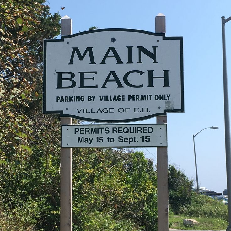 a sign for main beach parking by village permit only