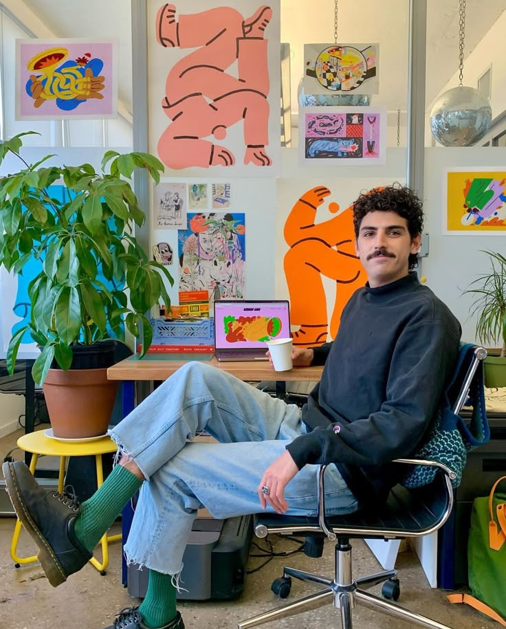 a man sitting in an office chair next to a plant