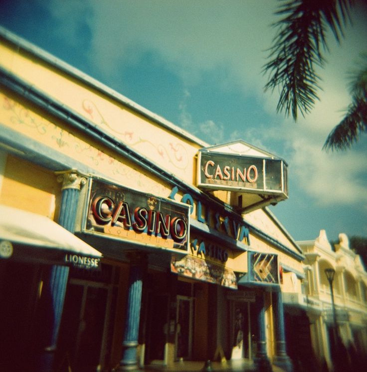 a casino sign on the side of a building with palm trees in the foreground