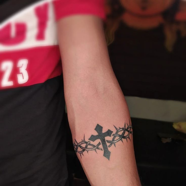 a man with a cross tattoo on his arm