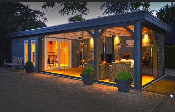 a small house is lit up at night with lights on the porch and patio area