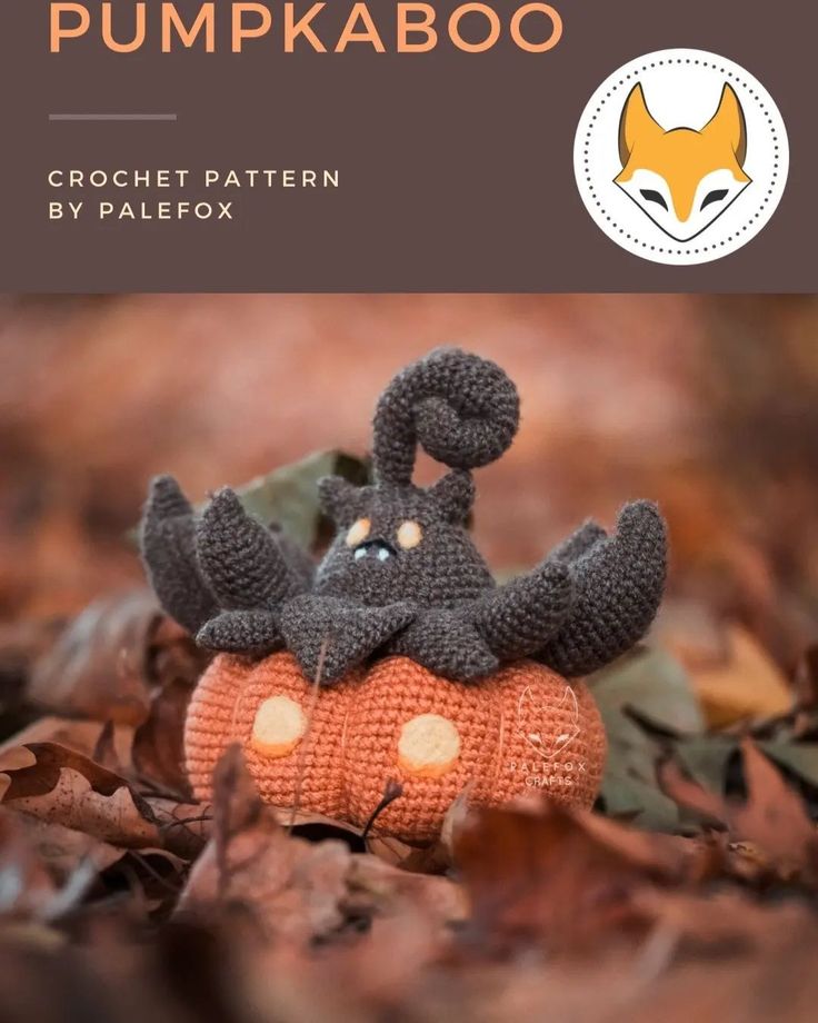 a crocheted pumpkin with an animal on it's head sitting in the leaves