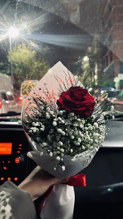 a person holding a bouquet of flowers in their hand on the dashboard of a car