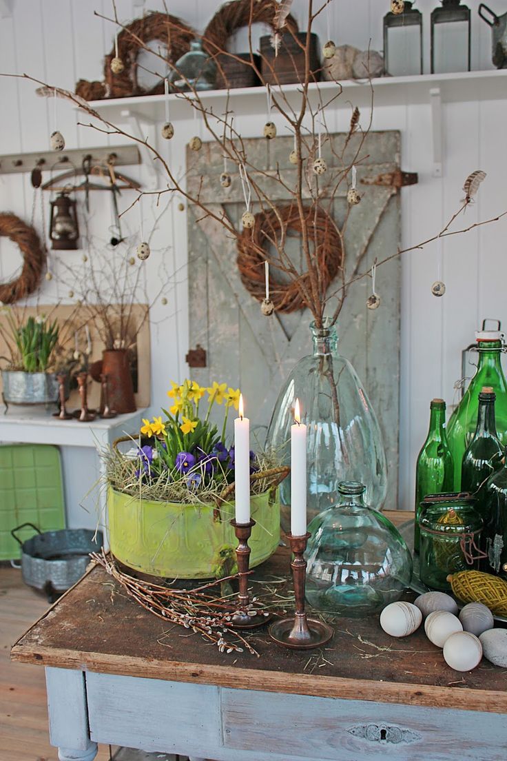 a table topped with lots of vases filled with flowers and candles next to bottles