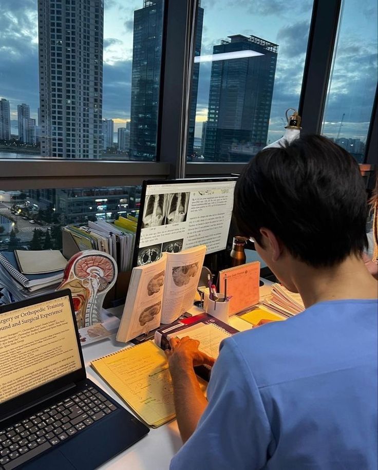 a young man sitting at a desk using a laptop computer