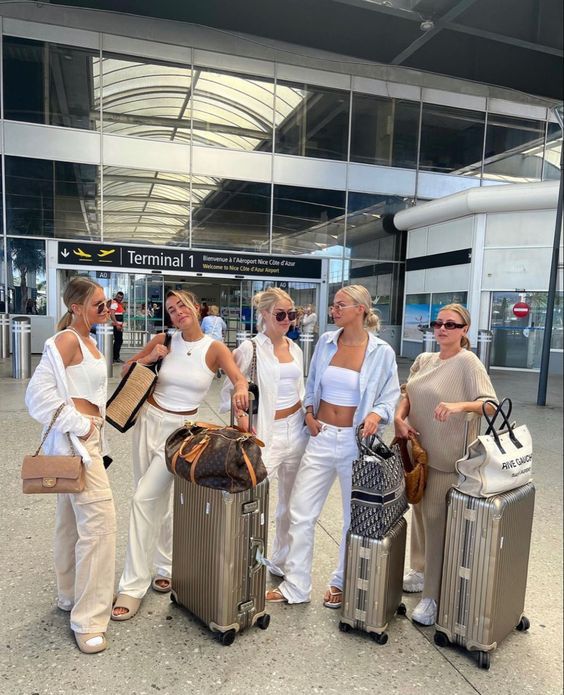 four women are standing with their luggage at the airport