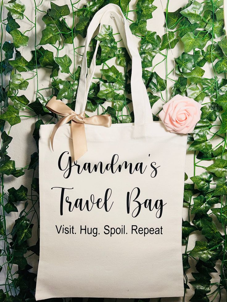 a white bag with the words grandma's travel bag and a pink rose on it