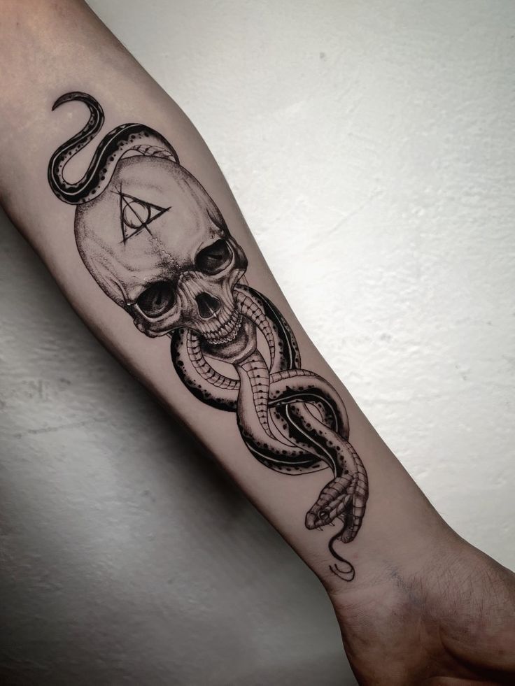 a skull and octopus tattoo on the arm with an all seeing triangle in it's center