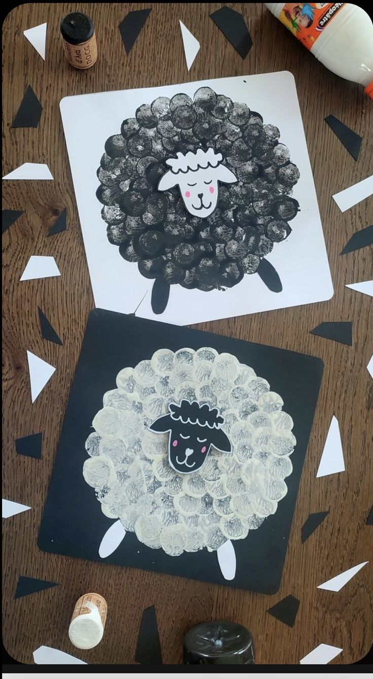 two sheep made out of black and white paper on a table with confetti