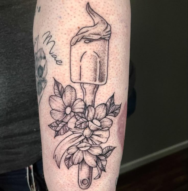 a person with a tattoo on their arm holding an ice cream cone and flower bouquet