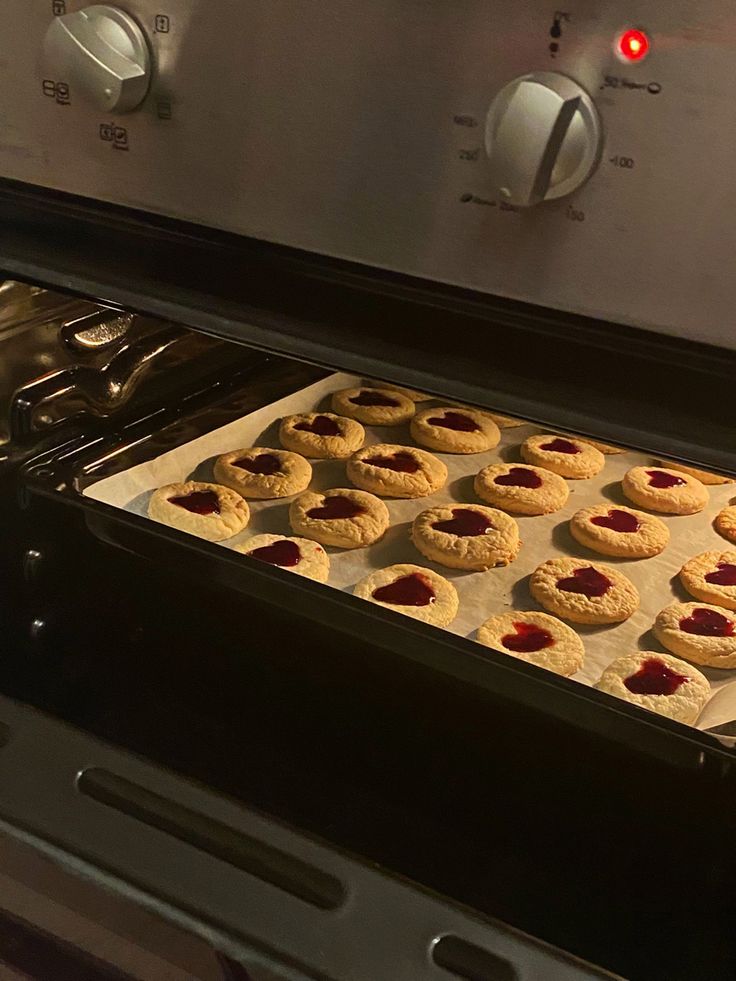 cookies are baking in an oven with the door open to show them on parchment paper