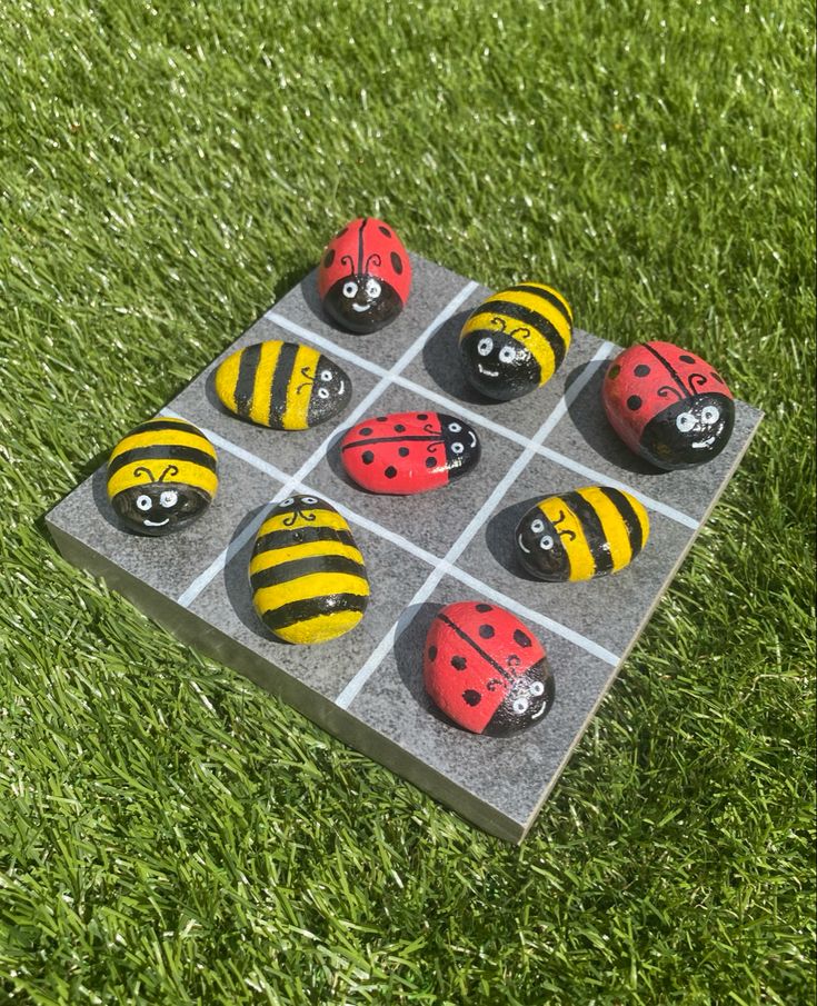 a set of six painted ladybugs sitting on top of a grass covered field