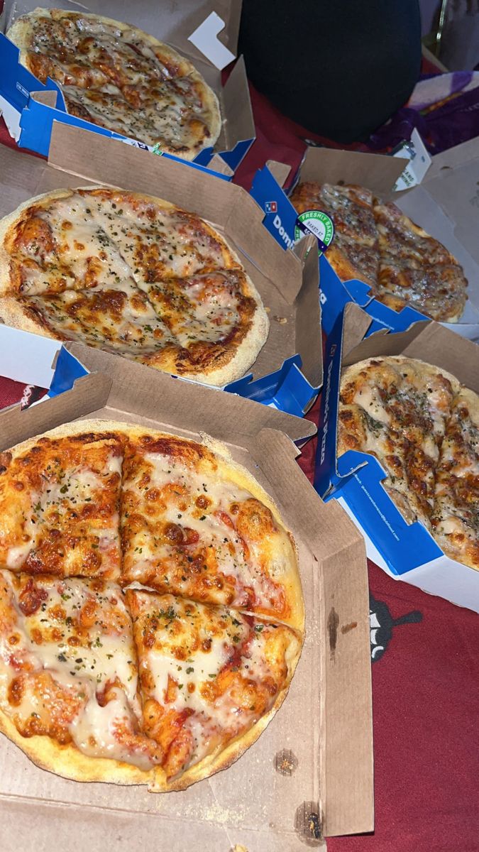 four pizzas sitting in boxes on a table