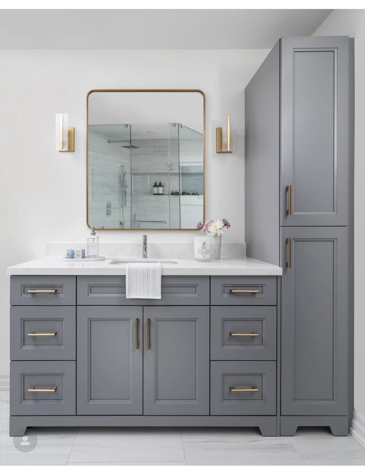 a bathroom with gray cabinets and a large mirror