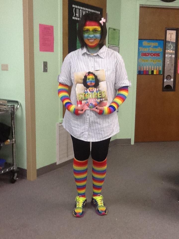 a person with clown makeup and colorful socks holding a book in an office building hallway