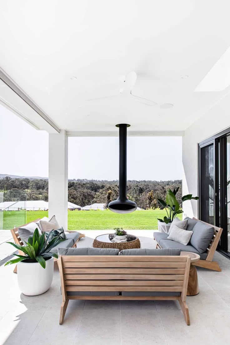 an outdoor living area with couches, tables and potted plants