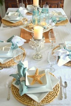 the table is set with plates, silverware and starfish napkins on it