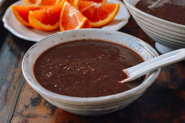 two white bowls filled with chocolate pudding and orange slices on a table next to other plates