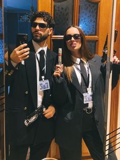 a man and woman standing in front of a mirror taking a selfie with their cell phones