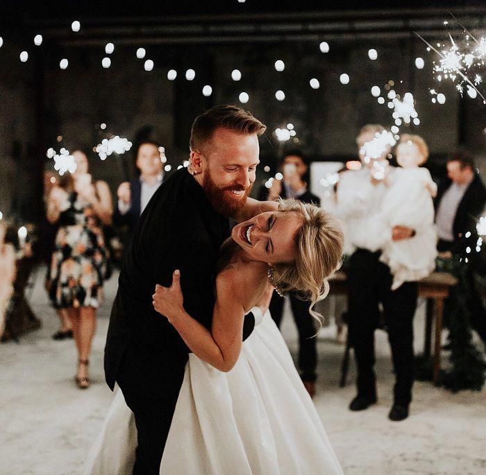 a bride and groom share their first dance with sparklers in the background