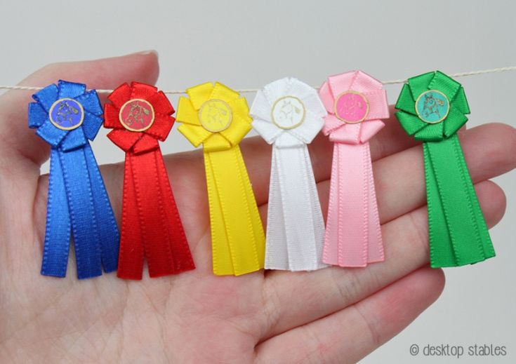 a hand holding five different colored ribbons