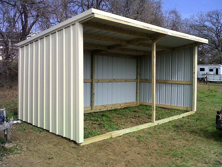 a large metal shed sitting on top of a grass covered field