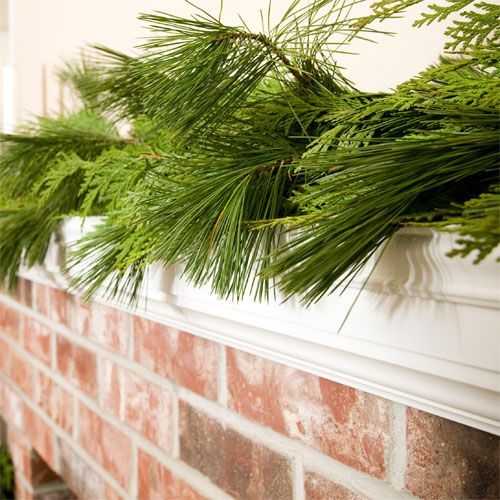 a close up of a brick fireplace with pine needles on it's mantel