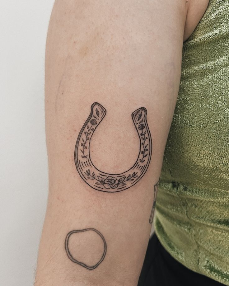 a woman's arm with a tattoo on it that has a horseshoe in the middle