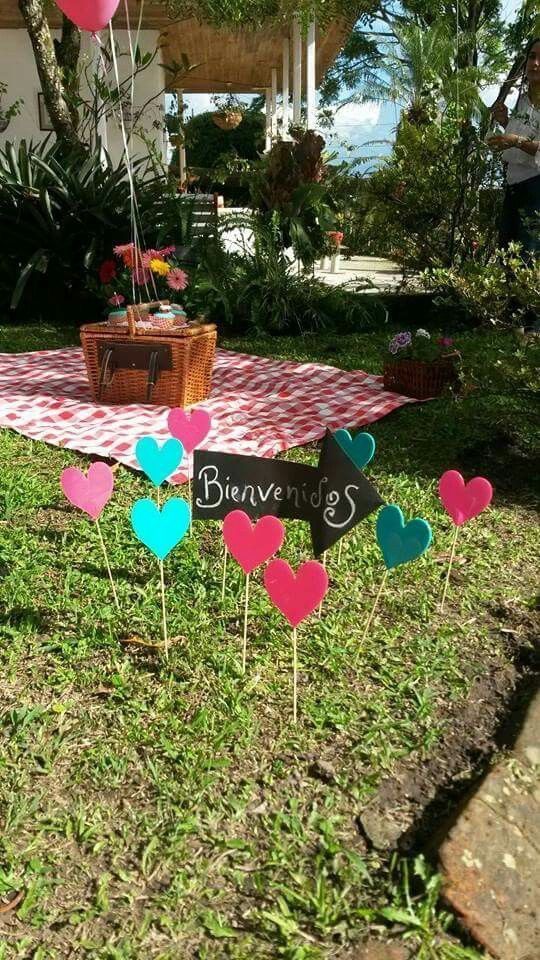 some heart shaped signs are sitting in the grass near a picnic table and potted plant