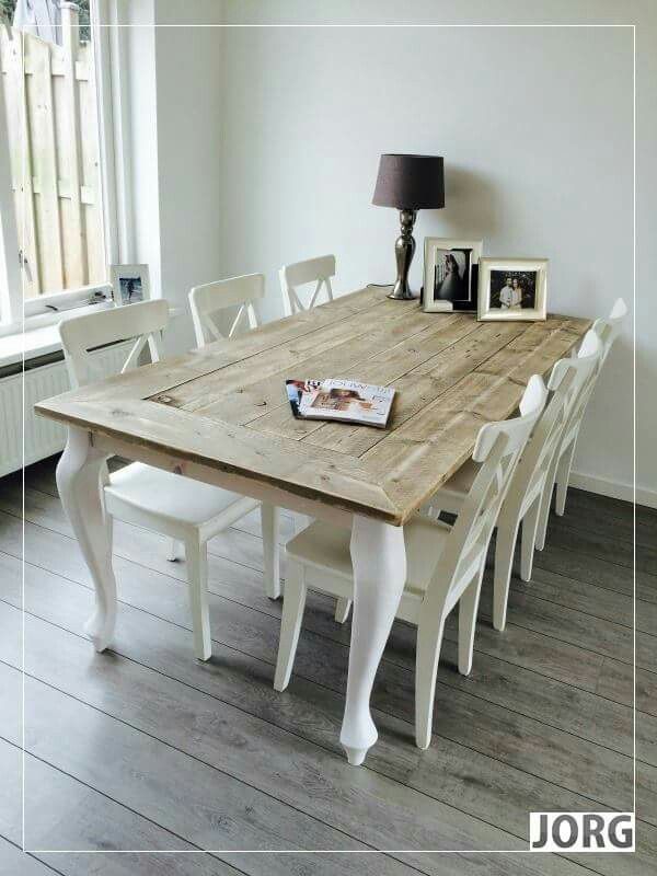 a wooden table with white chairs and pictures on the wall next to an open window