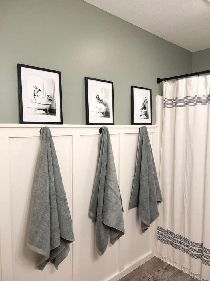 three towels hanging on the wall next to two framed pictures and a shower curtain in a bathroom